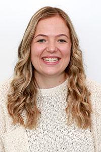 blonde woman smiling wearing a cream sweater